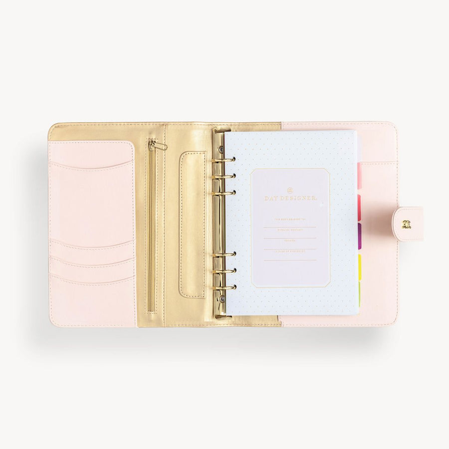 Open blush A5 vegan leather planner with, gold lining and colorful refill pages, and a gold clasp on the front cover.