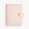 A blush A5 vegan leather planner with a gold clasp on the front cover.