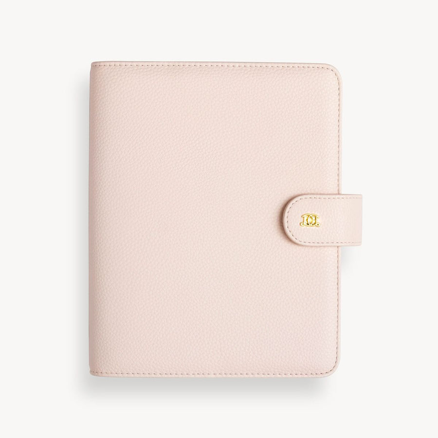 A blush A5 vegan leather planner with a gold clasp on the front cover.